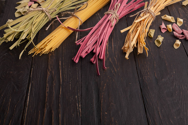 Hromadu fialové a zelené fettuccine těstoviny na dřevěné pozadí - Fotografie, Obrázek