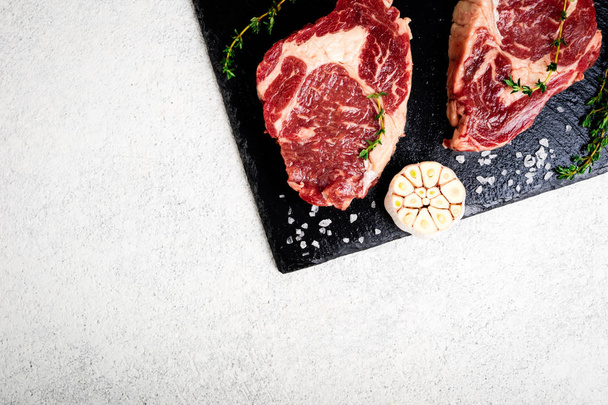 牛肉のステーキとまな板の上の食材。コンクリート白地生肉。平面図です。コピー スペース - 写真・画像