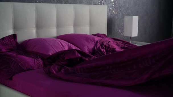 zieht die violette Decke herunter und deckt sie über dem Bett zu - Filmmaterial, Video