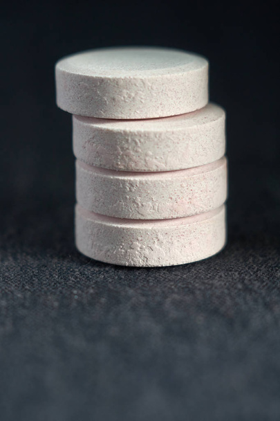 stack white pills on black textile background. medical pharmacy - Zdjęcie, obraz