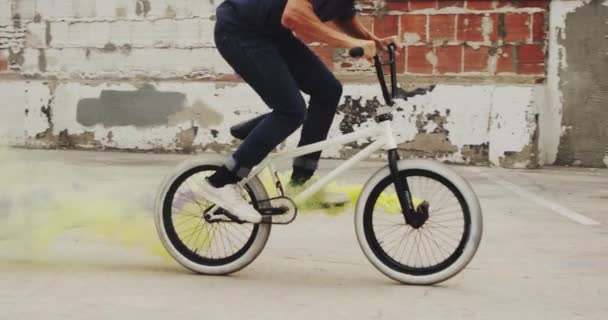 Extreme Bmx ποδηλάτης κάνει ουρά μαστίγιο κόλπο με μοβ και κίτρινο χρωματισμένο χειροβομβίδα καπνού σε αστικό περιβάλλον - Πλάνα, βίντεο