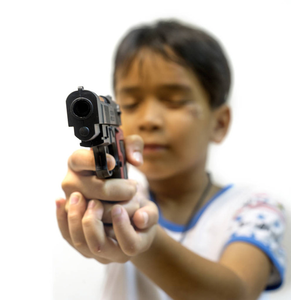 若い男の子、おもちゃの銃を持って、白い背景に対して. - 写真・画像