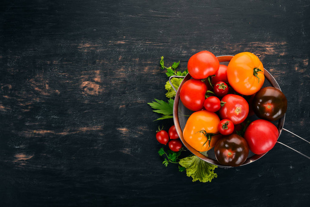 Fresh Tomatoes in a metal basket. On a wooden background. Top view. Copy space. - 写真・画像