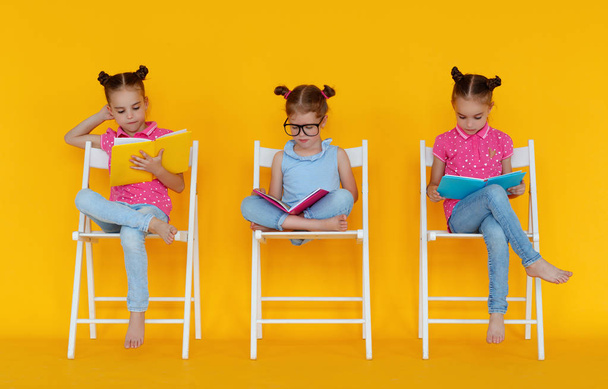 divertido niños niñas leer libros sobre un fondo de color amarillo
 - Foto, Imagen