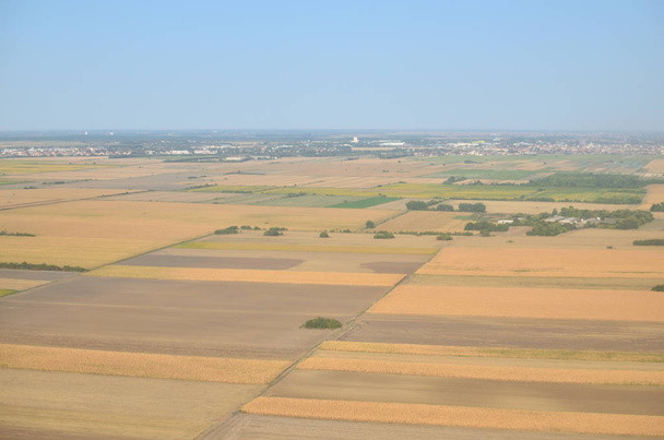 Llanuras con diferentes cultivos y plantas y un suburbio de la ciudad visto desde un avión de aterrizaje
 - Foto, imagen
