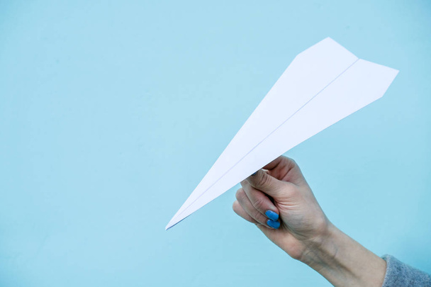 Ruka držící papírové letadlo na světle modrém pozadí.  - Fotografie, Obrázek