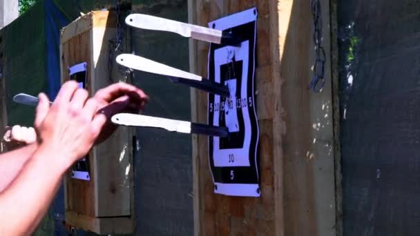 Men's hands get a knife from the target. Throwing knives at the target from an open-air distance, a competition for throwing knives, flying knives, Sharp knives stick out of a wooden stand with a target, side view, slow motion - Footage, Video