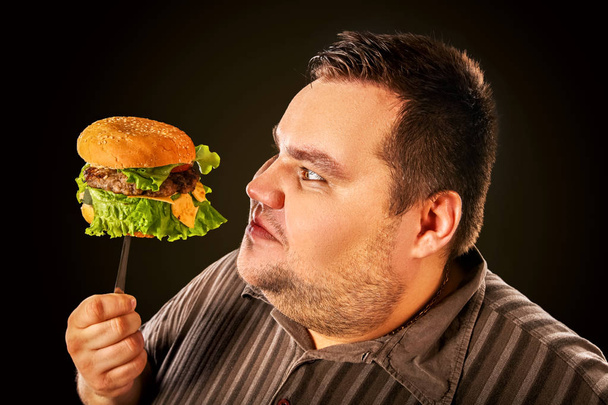 Lihava mies syö pikaruokaa. Aamiainen ylipainoisille
. - Valokuva, kuva
