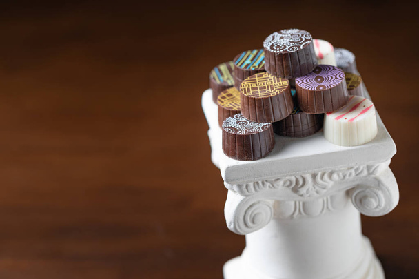 Пачка тонких шоколадных конфет, сложенных на белом столбе
. - Фото, изображение
