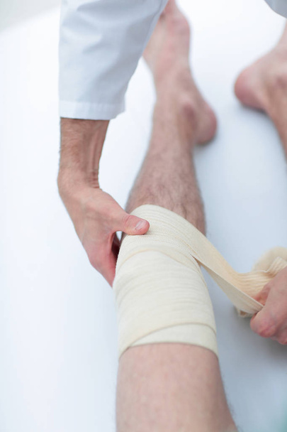 closeup. doctor bandaging a patients leg - Foto, afbeelding