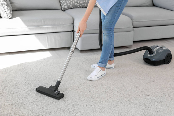 Woman removing dirt from carpet with vacuum cleaner at home - Photo, Image