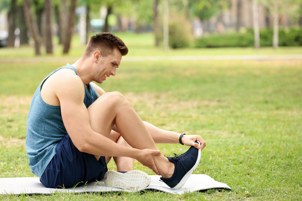 Male athlete suffering from foot pain during training outdoors - Foto, immagini
