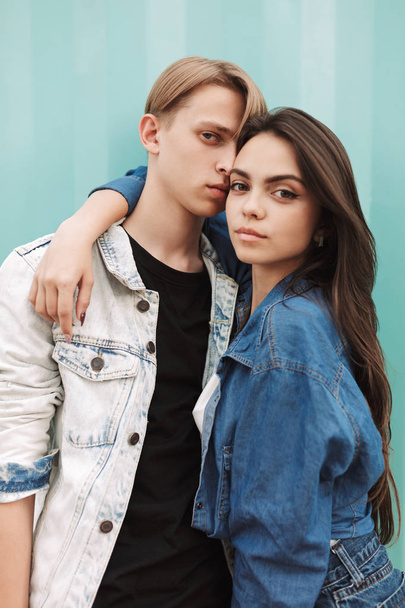 Portrait of young couple standing and looking in camera while spending time together on over blue background - Фото, изображение