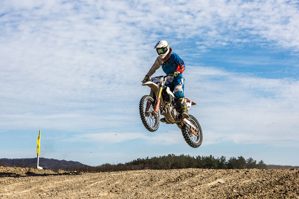 Rennfahrer auf Motorrad im Flug, springt und hebt mit Sprungbrett gegen den Himmel ab. - Foto, Bild