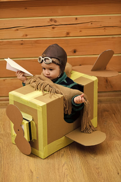 Gyerekek, játék - boldog játék. Kis álmodozó fiú játék-val egy karton repülőgép. - Fotó, kép