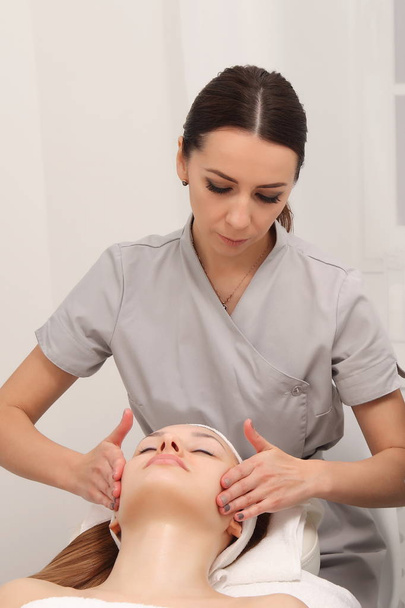 facial treatment of a young woman in a cosmetology salon - Fotoğraf, Görsel