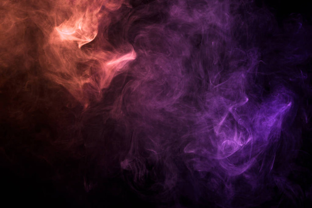 Dense multicolored smoke of  pink and red colors on a black isolated background. Background of smoke vape - Foto, imagen