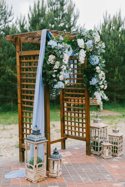 Floral arch with blue cloth and wooden elements at a rustic  wedding ceremony - 写真・画像
