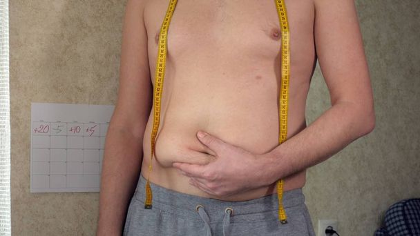 Un hombre gordo mide su cintura, una gran barriga de cerveza, un estilo de vida saludable recoge pliegues de grasa
 - Foto, Imagen