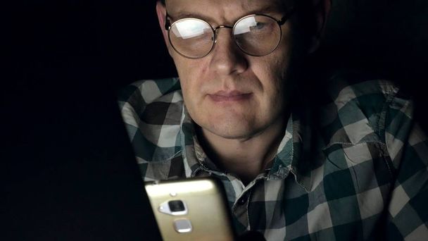 Muž v brýlích pracuje v noci. On vypadá strach, on vidí na obrazovce počítače před ním, detail - Fotografie, Obrázek