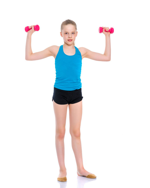 Little girl doing exercises with dumbbells. - Foto, imagen