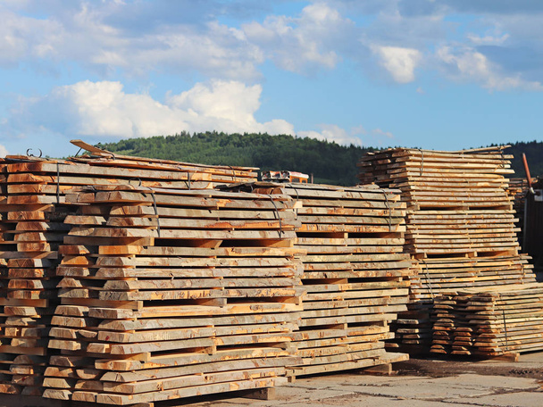 Grandes planches de bois empilées dans des racks pour sécher sous le ciel ouvert dans une zone industrielle. Timing du bois pour la menuiserie. Fabrication de meubles et d'articles en bois. Se débarrasser de l'humidité ligneuse
. - Photo, image