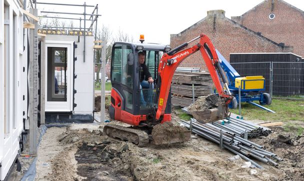 Guindaste pequeno está nivelando chão em um local de construção de uma casa holandesa - Foto, Imagem