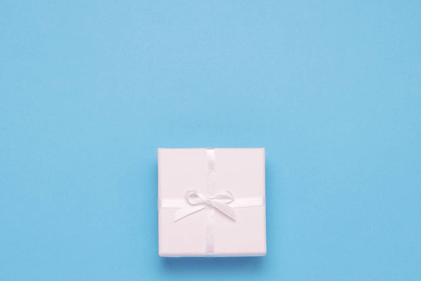 Mavi bir arka plan üzerinde beyaz hediye kutusu. Minimalist tarzı. Düz yatıyordu, en iyi görünümü. - Fotoğraf, Görsel