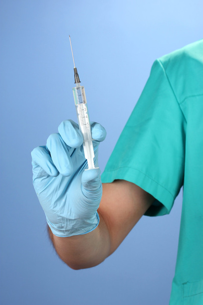 Doctor with syringe on blue background - Foto, imagen