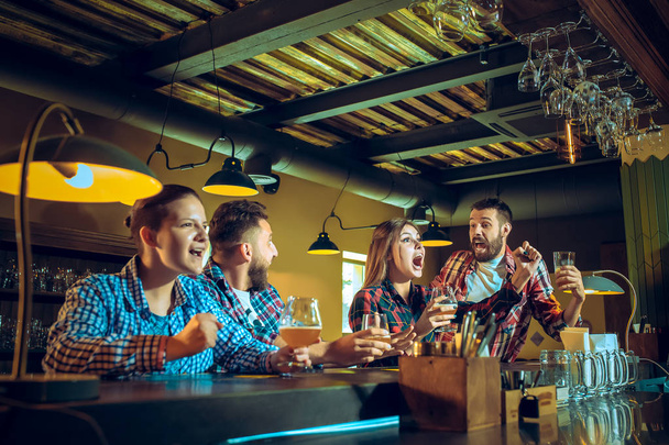 Sport, people, leisure, friendship and entertainment concept - happy football fans or male friends drinking beer and celebrating victory at bar or pub - Photo, image