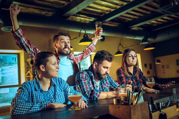 Sport, people, leisure, friendship and entertainment concept - happy football fans or male friends drinking beer and celebrating victory at bar or pub - Fotoğraf, Görsel