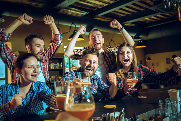 Sport, people, leisure, friendship and entertainment concept - happy football fans or male friends drinking beer and celebrating victory at bar or pub - Foto, Imagem