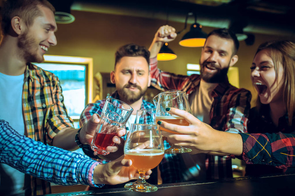 Sport, people, leisure, friendship and entertainment concept - happy football fans or male friends drinking beer and celebrating victory at bar or pub - Foto, Bild