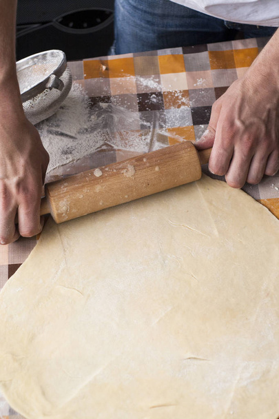 Cooking and home concept - close up of male hands kneading dough on a background in cell - Foto, imagen