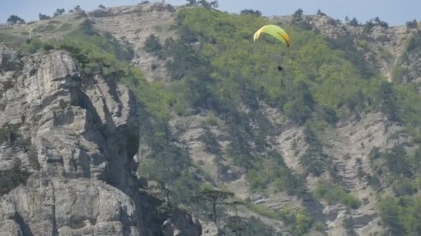 El parapente amarillo vuela sobre un fondo de verdes montañas rocosas de Crimea
 - Metraje, vídeo