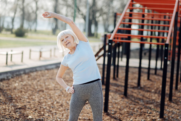 Alert old woman exercising outdoors - Foto, Imagen