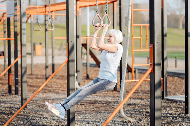 Determined old woman doing chin-ups - Photo, Image