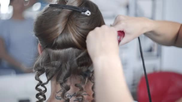 Στυλίστας κάνει σγουρά Άφρο hairstyle για γυναίκα από καυτό Κέρλινγκ μαλλιά, διαδικασία της λήψης χτένισμα, χτενίσματα στο σαλόνι ομορφιάς - Πλάνα, βίντεο