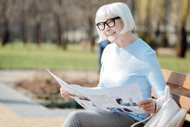 Exuberant old woman reading a newspaper - 写真・画像