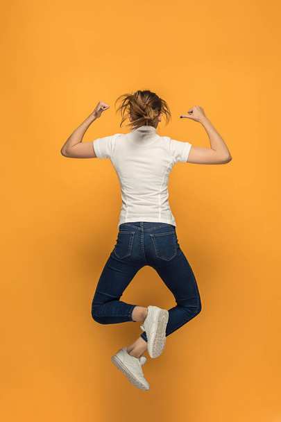 Closeup of young womans body in empty white t-shirt on orange background. Mock up for disign concept - Foto, Imagen