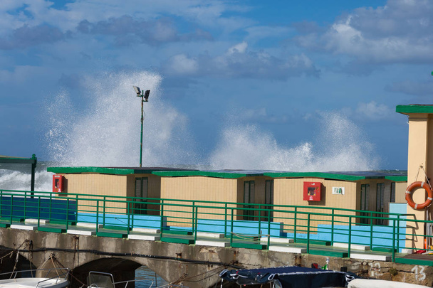 Tengeri hullámok törés ellen fa tengerparti kunyhót szeles nap: viharos időjárás. - Fotó, kép