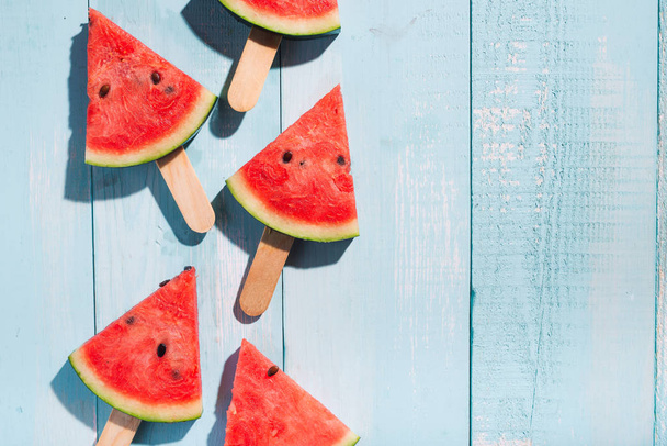 Slices of watermelon on blue wooden desk with copy space - Fotó, kép