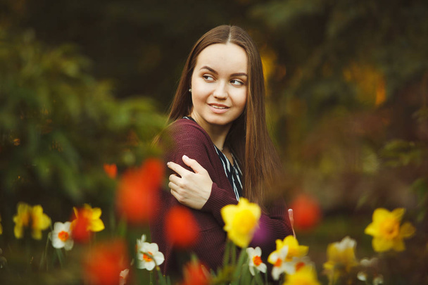 beautiful girl sits at the planted flowers. - Foto, Bild