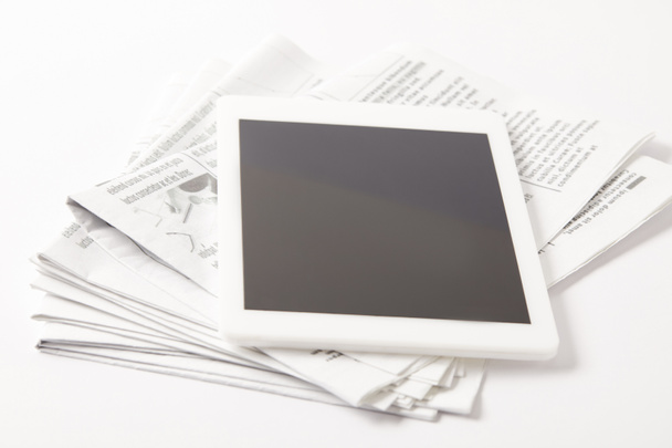 κοντινό πλάνο σωρό των εφημερίδων με ψηφιακό tablet, σε λευκό - Φωτογραφία, εικόνα