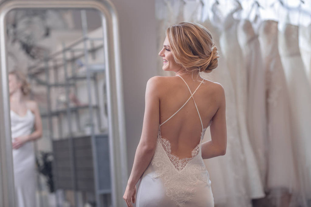 Attractive young bride at the mirror in the store - Foto, afbeelding
