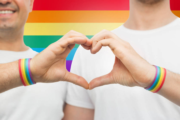 Schwules Paar mit Regenbogenarmbändern und Handherz - Foto, Bild