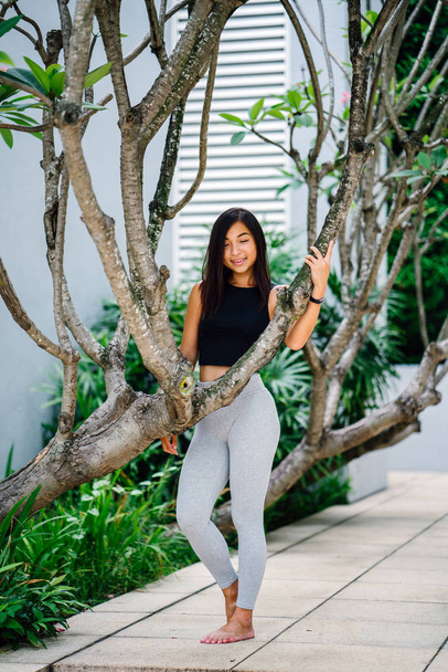 Portrait of an attractive, young Chinese Asian woman dressed in sporty, active wear in  green public park in Singapore during the day on the weekend. - Zdjęcie, obraz