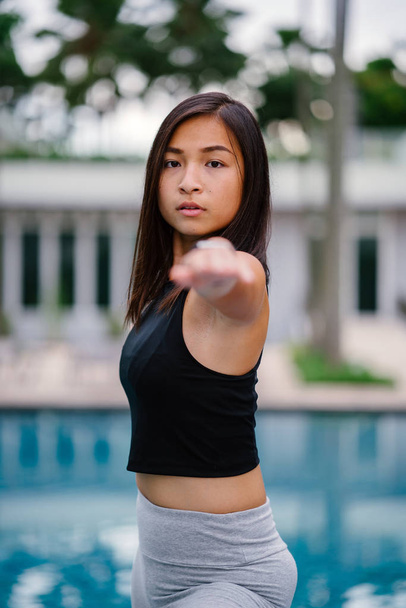 Ritratto di una giovane donna asiatica cinese attraente vestita con abbigliamento sportivo e attivo che fa yoga vicino alla piscina durante il giorno nel fine settimana
. - Foto, immagini