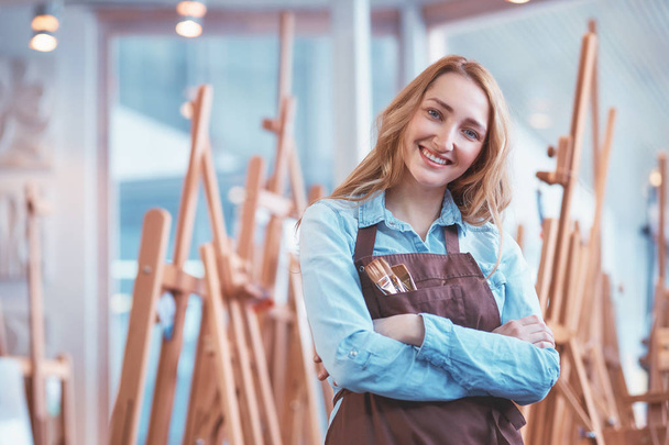 Attractive young artist with easels in studio - Photo, Image