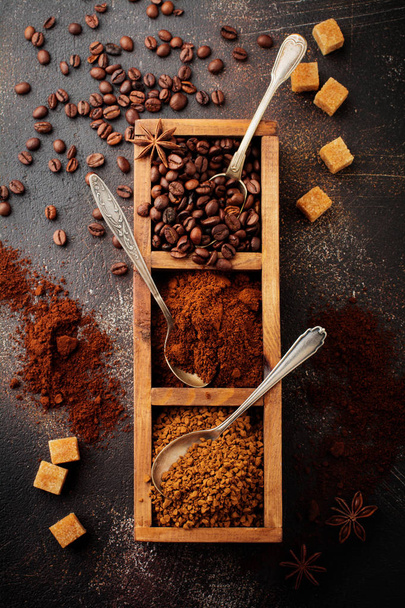 Food background with three kinds of coffee: beans, milled, instant in wooden box on old concrete brown background. Rustic stile. Selective focus. Top view. - Photo, Image